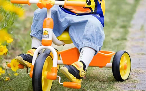 niño jugando con triciclo infantil amarillo