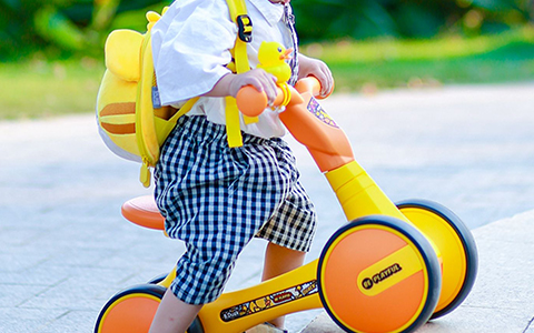 child playing with yellow ride on car